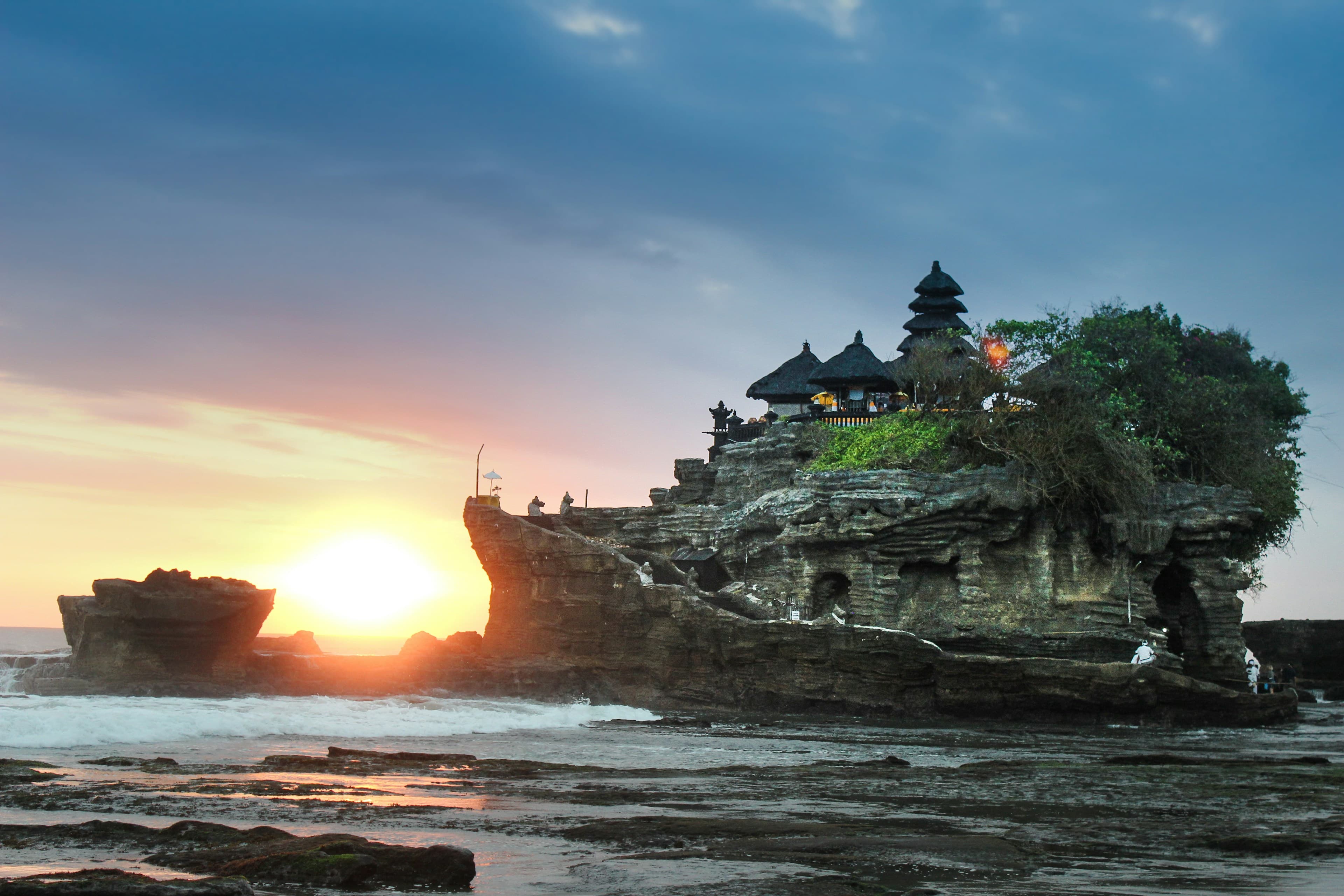 Bali ocean temple at sunset with golden light reflecting on the water