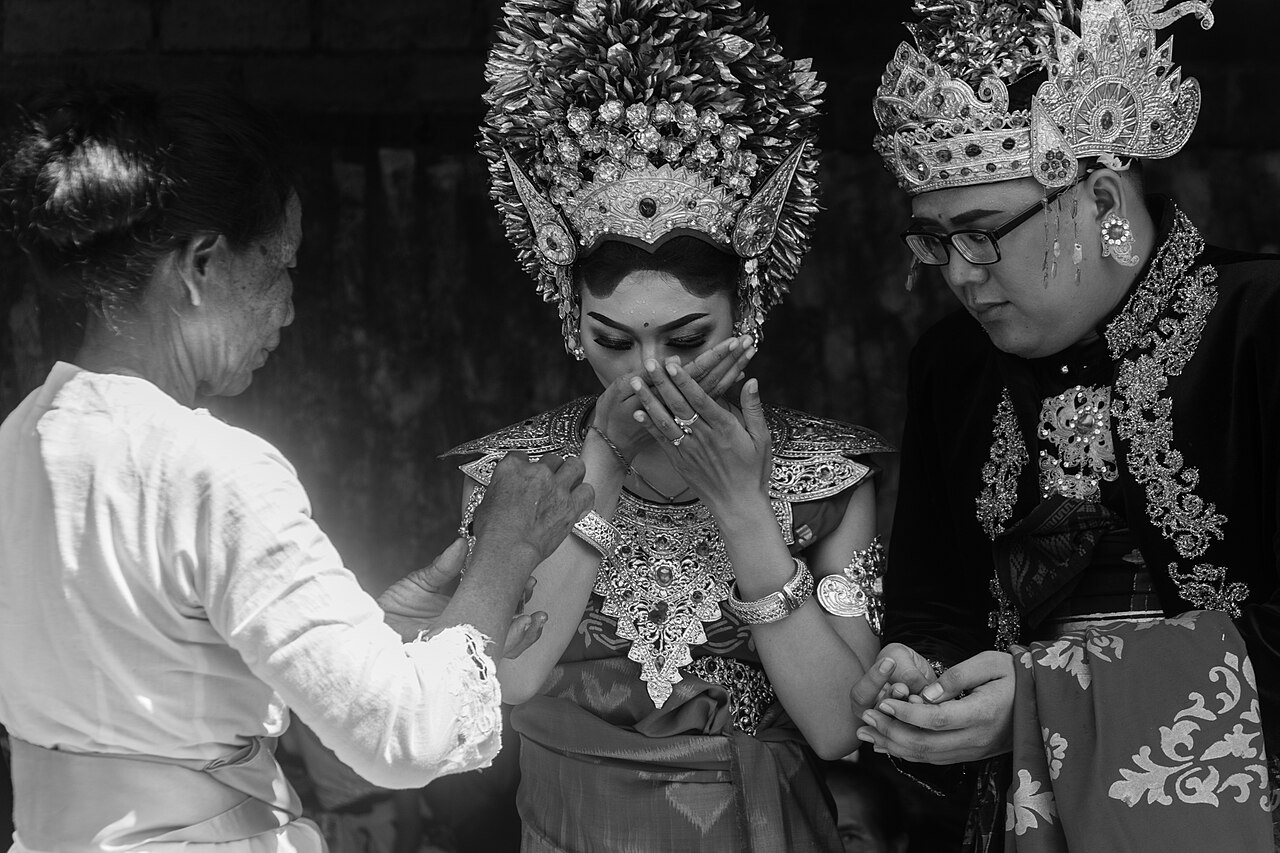 巴厘岛传统婚礼仪式中的新娘与新郎，身着金饰头冠与传统礼服。